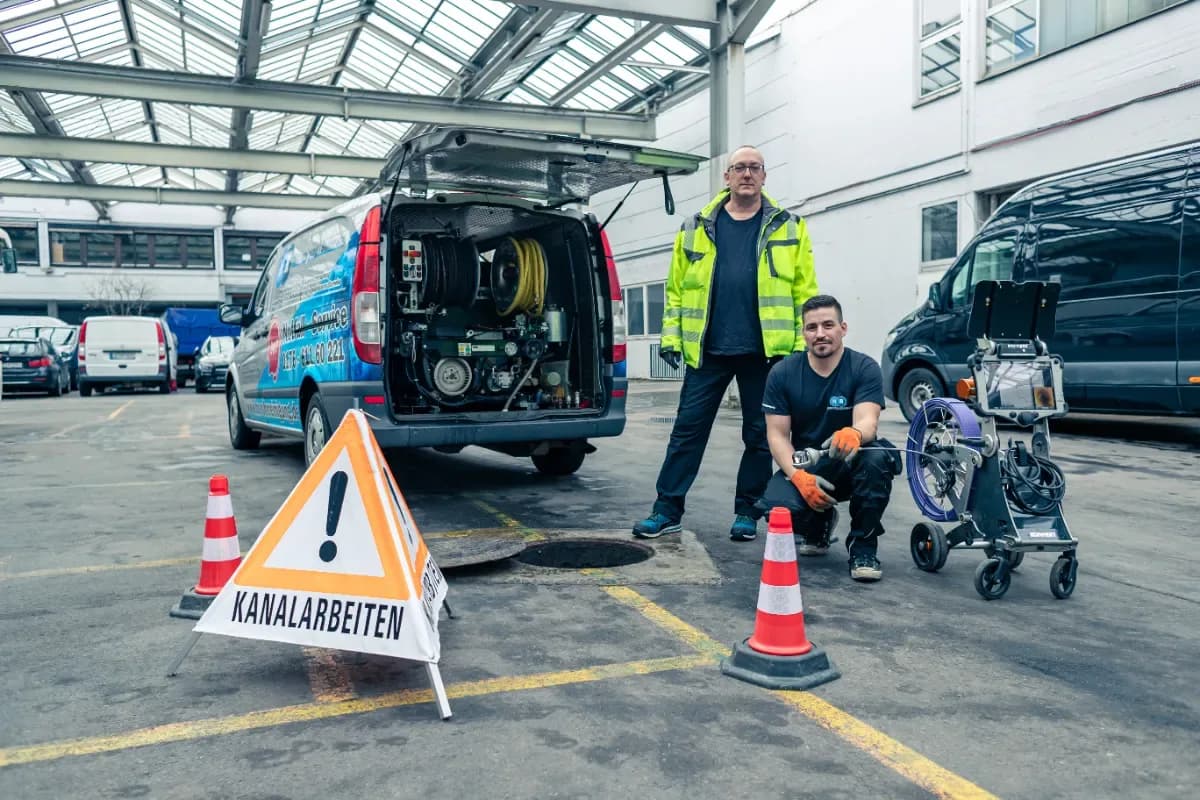 Team der HR Rohrreinigung/Sanierung mit Kamerawagen und Absperrung vor dem Einsatzfahrzeug